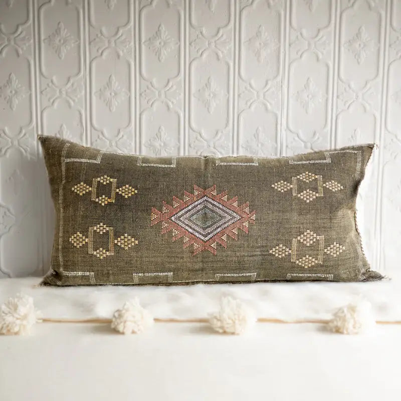 Decorative pillow with geometric patterns on a textured wall background