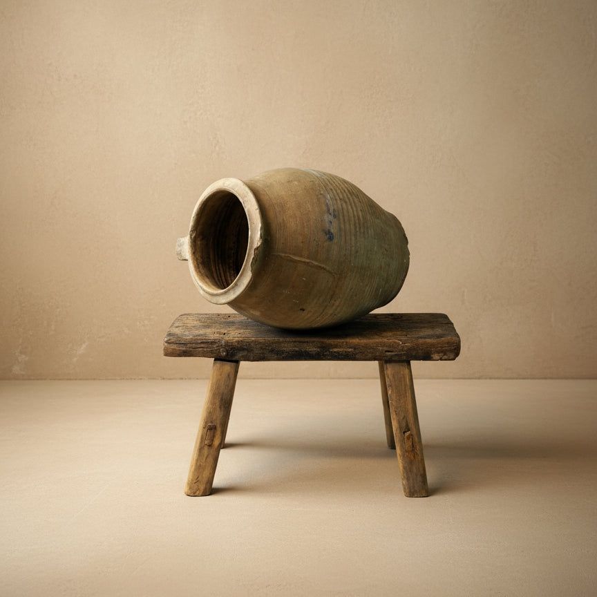 Vintage ceramic jar on a wooden stool against a white background