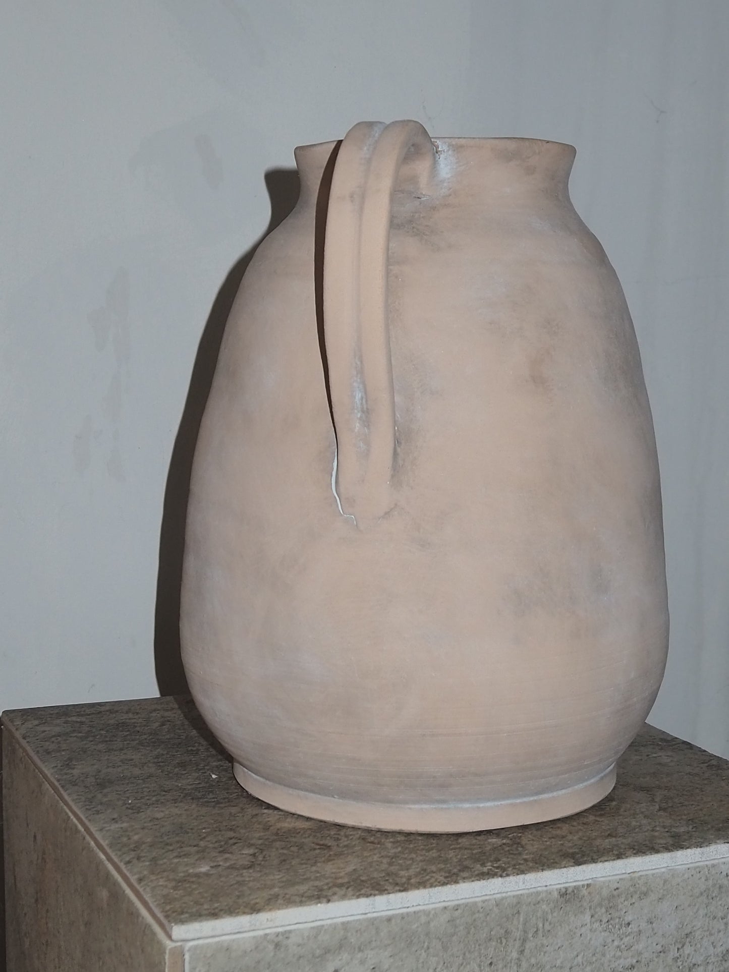 Ceramic vase with a handle on a plain background