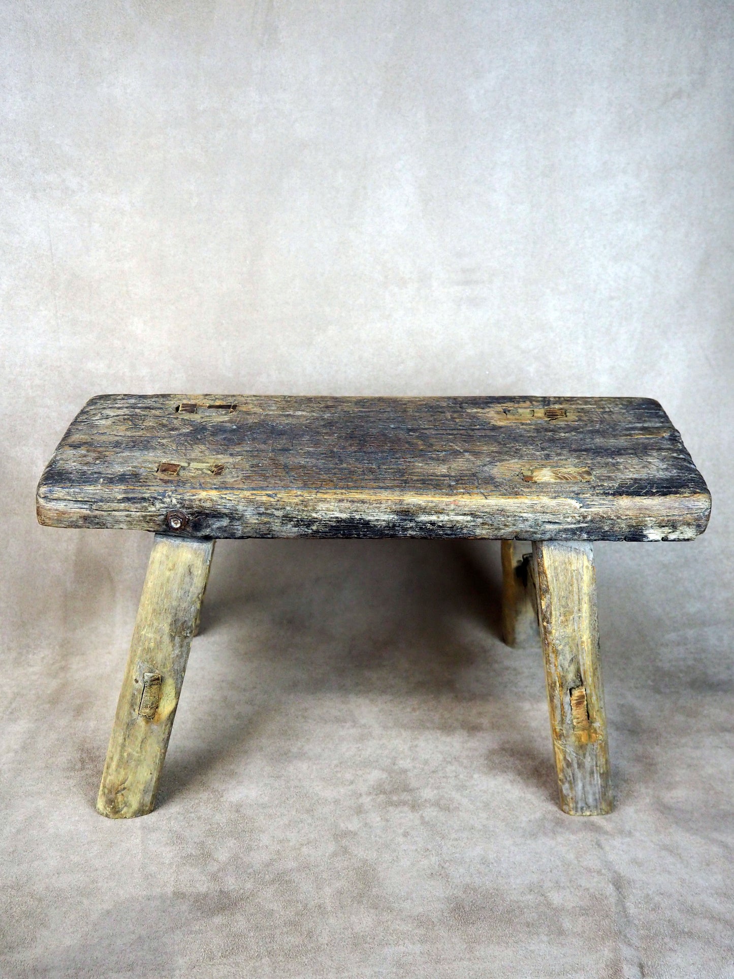 Vintage wooden bench with a weathered finish on a textured gray background