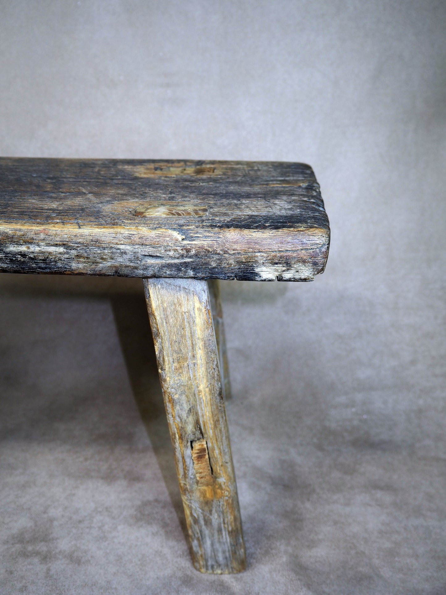Worn wooden bench against a plain background