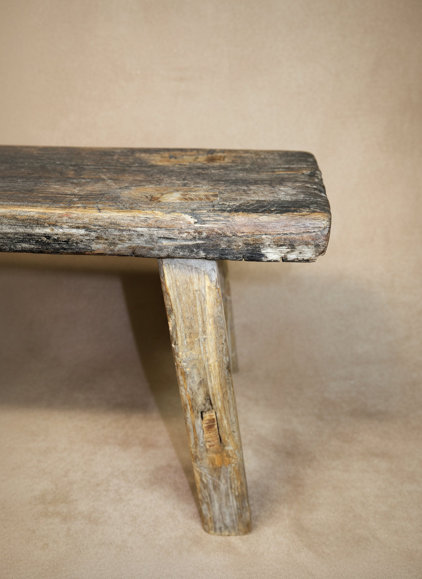 Worn wooden bench against a plain background