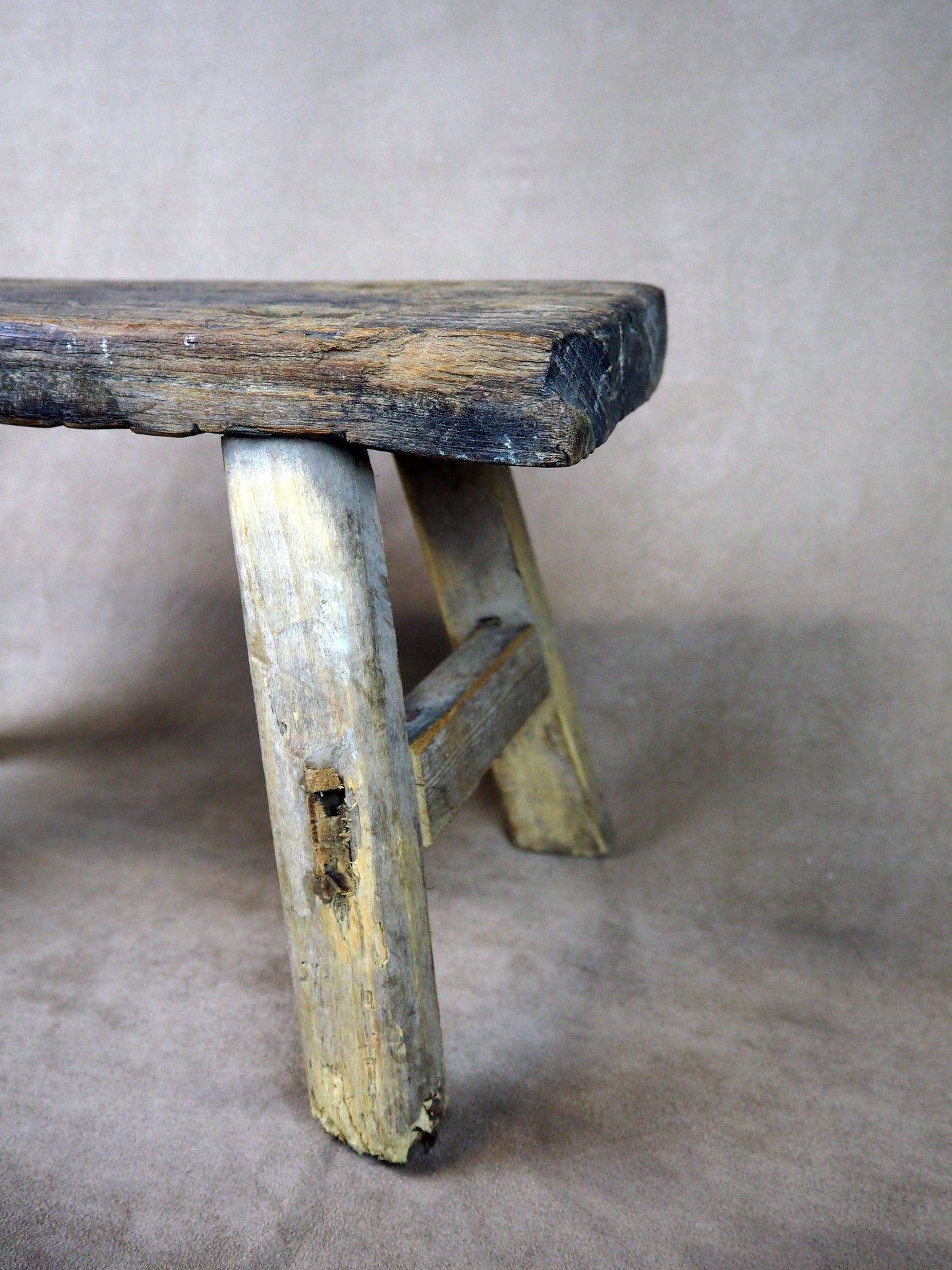 Vintage wooden stool with a worn surface on a plain background