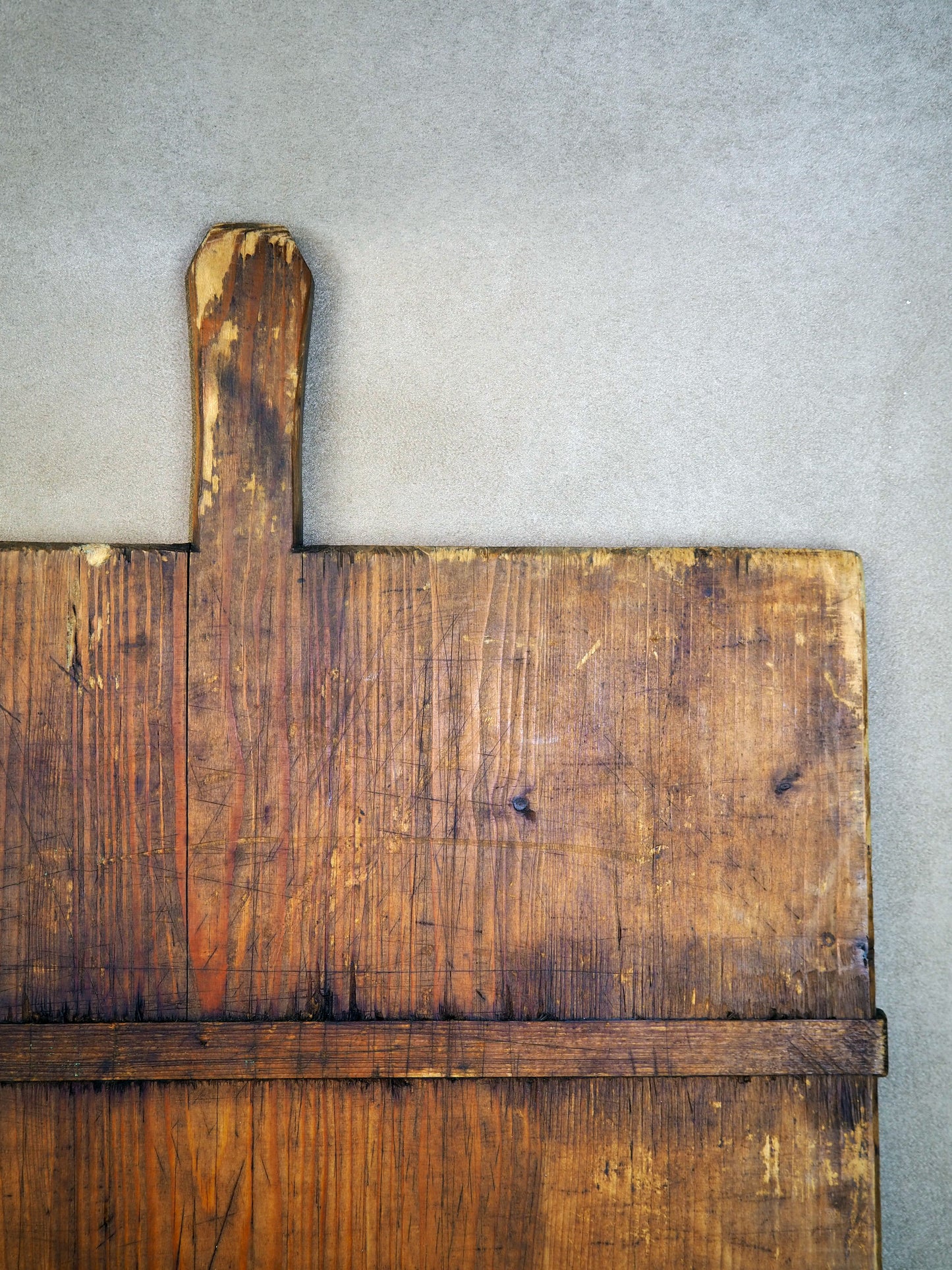 Old wooden cutting board with a handle on a gray background