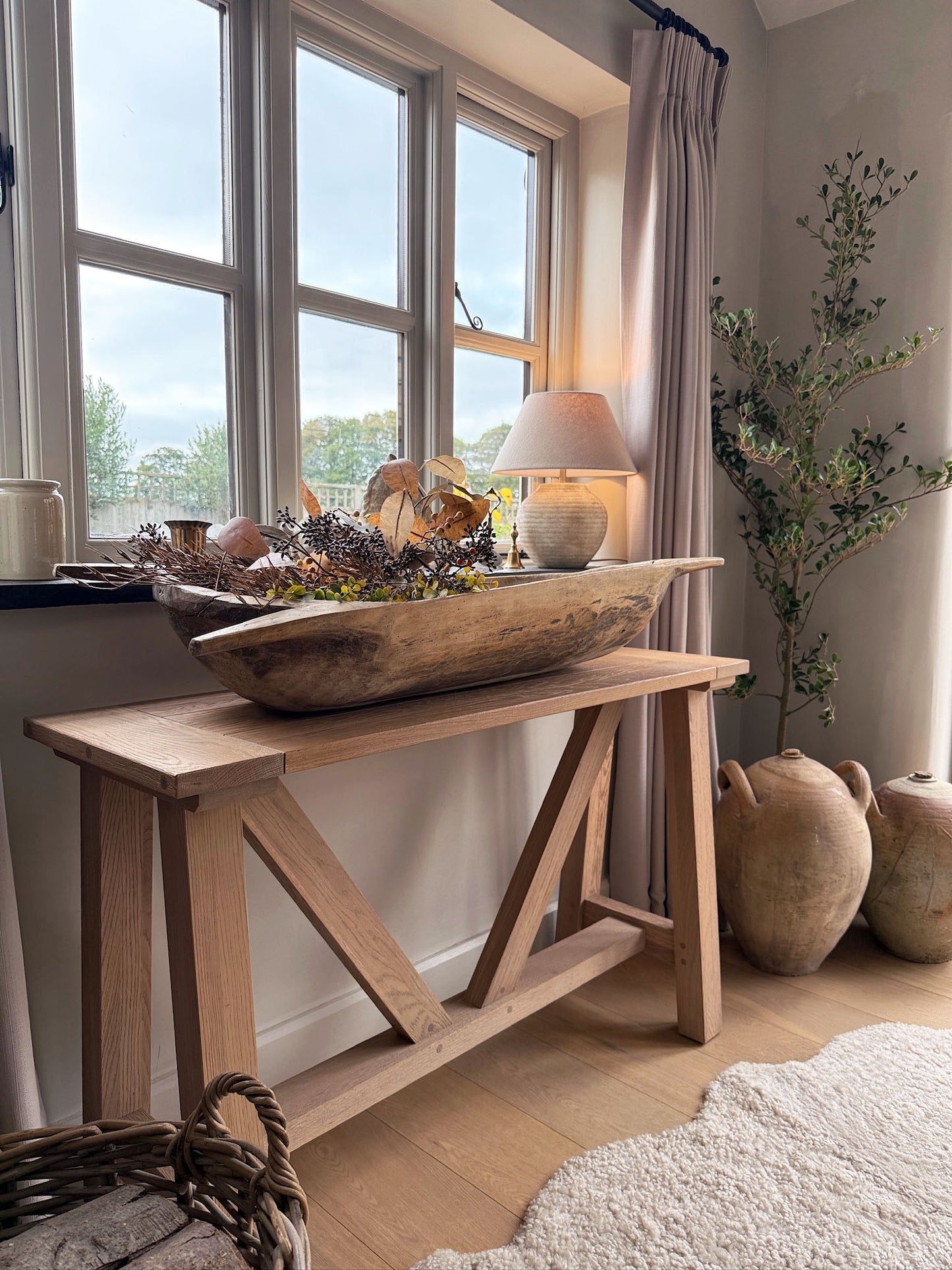 Wooden console table with decorative items in a room with large windows.