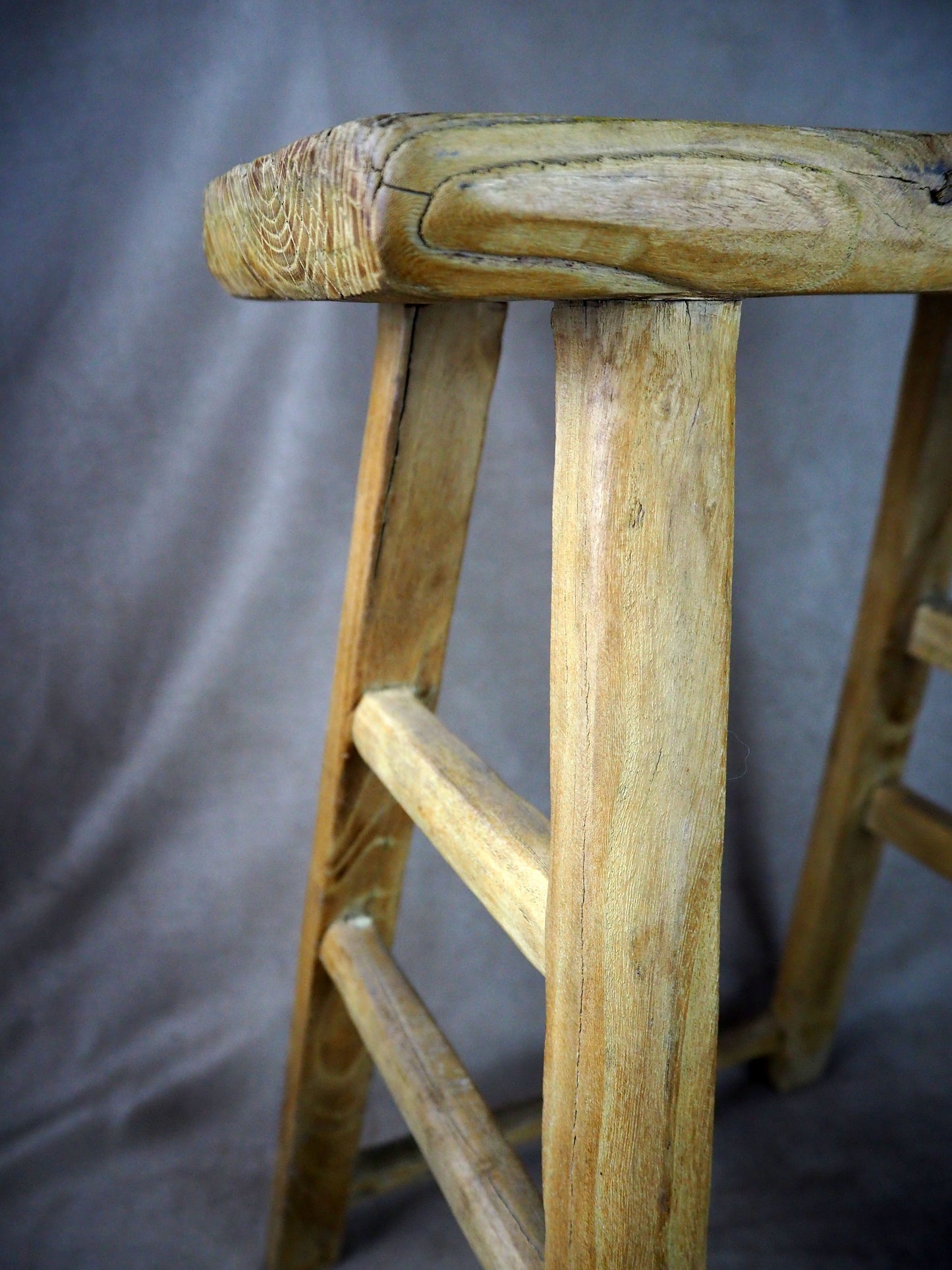 Close-up of a wooden stool with a gray background