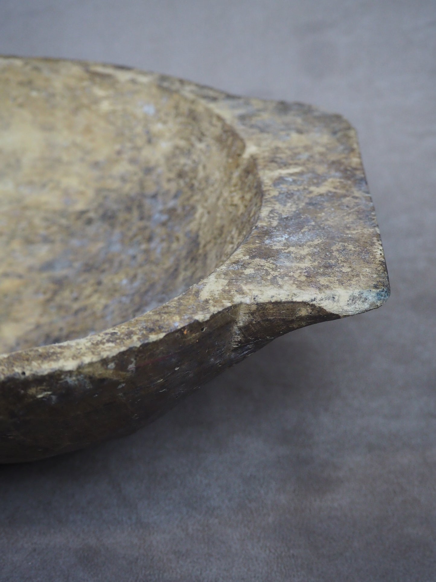 Close-up of an antique dough bowl with a textured surface on a gray background