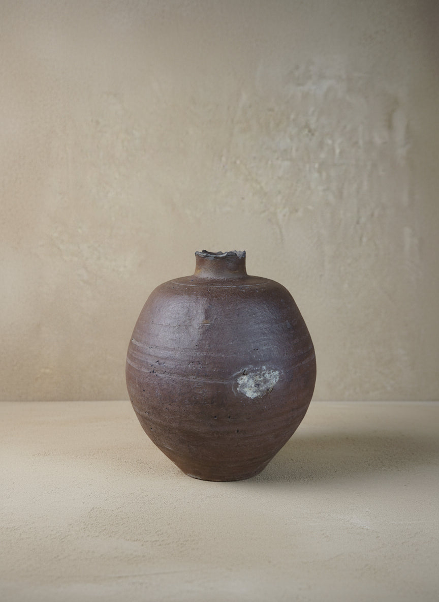 Purple ceramic vase on a wooden surface with a neutral background