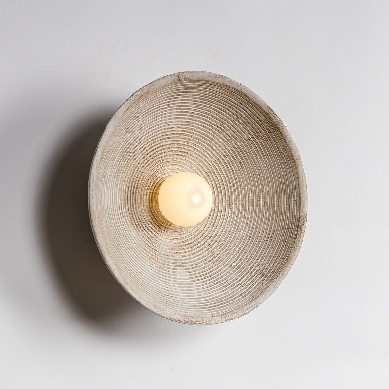 Round wall sconce with textured design on a light gray background