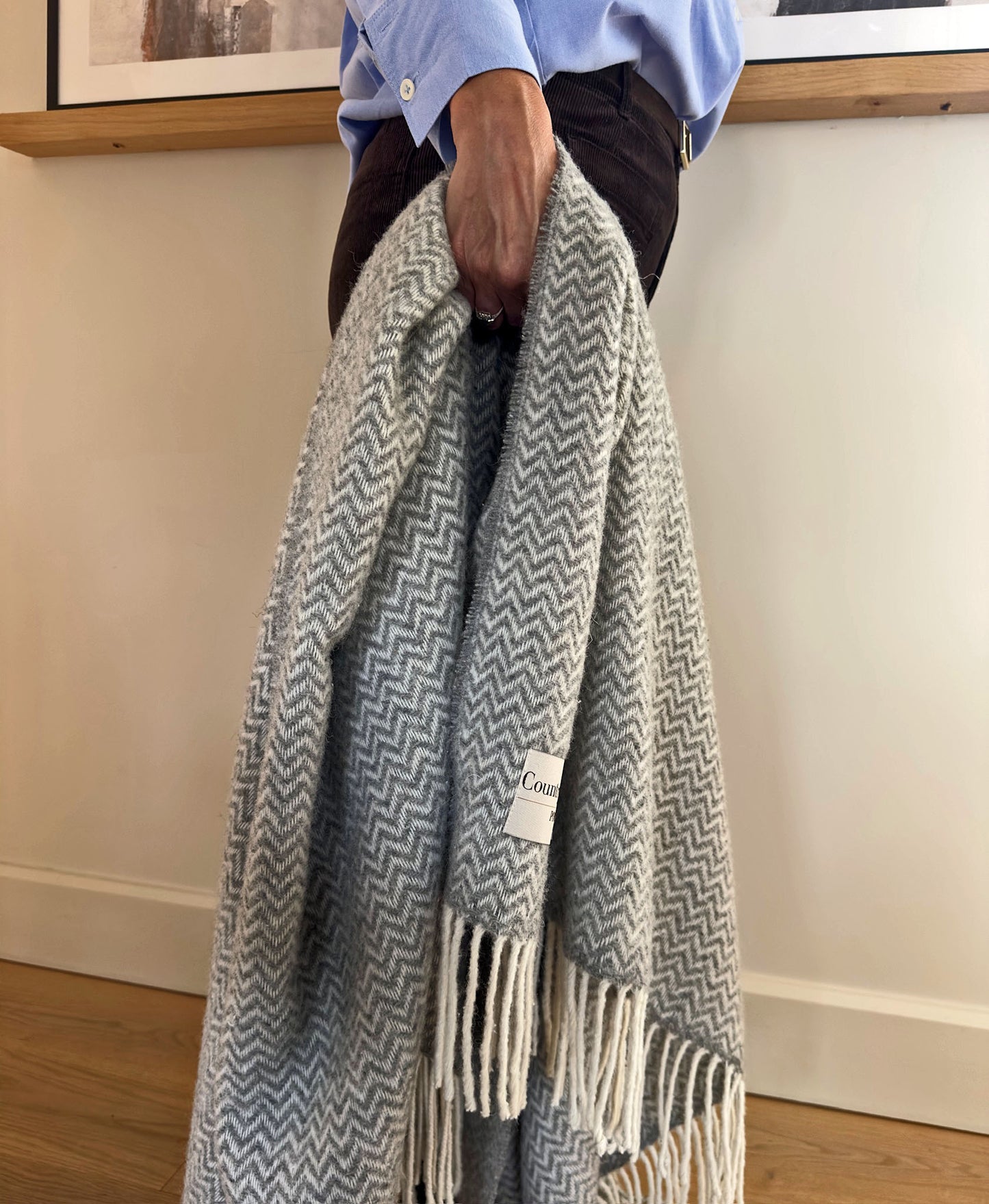 Person holding a gray and white patterned wool blanket.