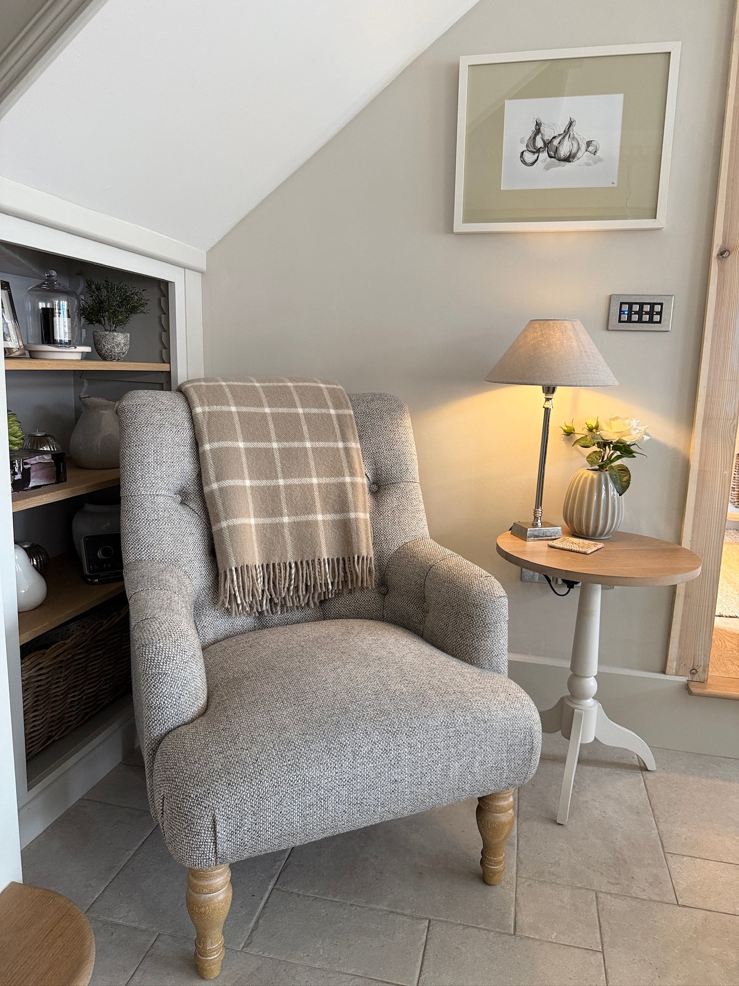 Gray armchair with a plaid blanket in a cozy living room setting.