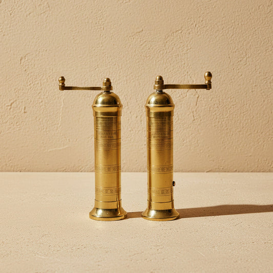 Pair of brass pepper mills on a white background
