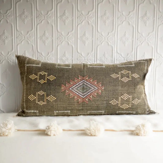 Decorative pillow with geometric patterns on a textured wall background