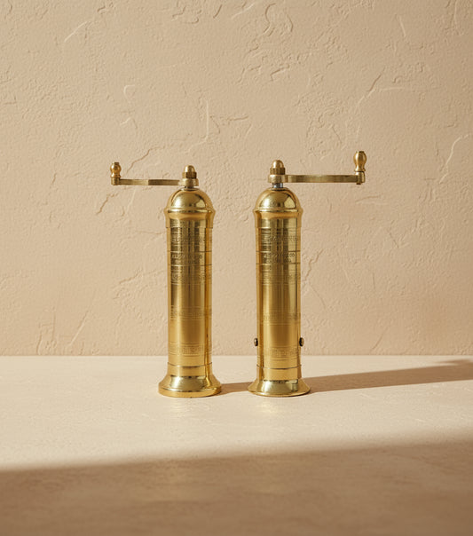 Pair of brass pepper mills on a white background