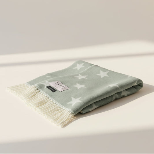 Folded light green blanket with star pattern on a beige surface