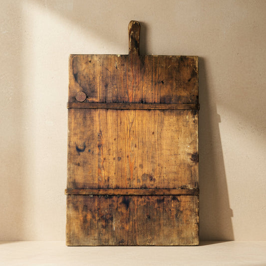 Vintage wooden cutting board with a handle on a beige background