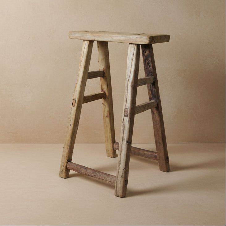 Wooden stool with a textured surface on a gray background