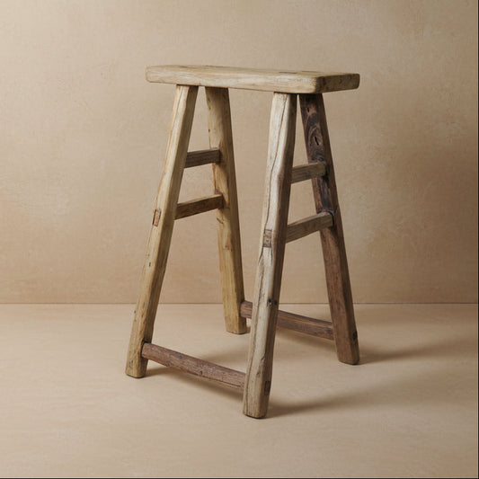 Wooden stool with a textured surface on a gray background