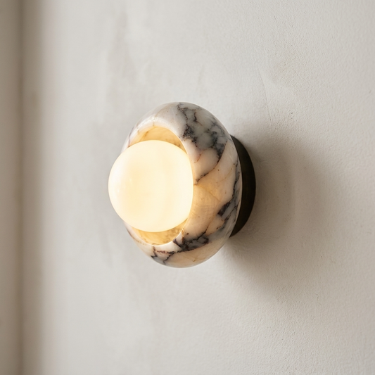 Wall-mounted light fixture with marble-like finish on a plain wall.