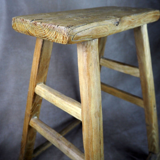 Wooden elm stool against a gray background
