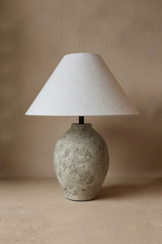 Table lamp with a textured ceramic base and white lampshade on a beige background