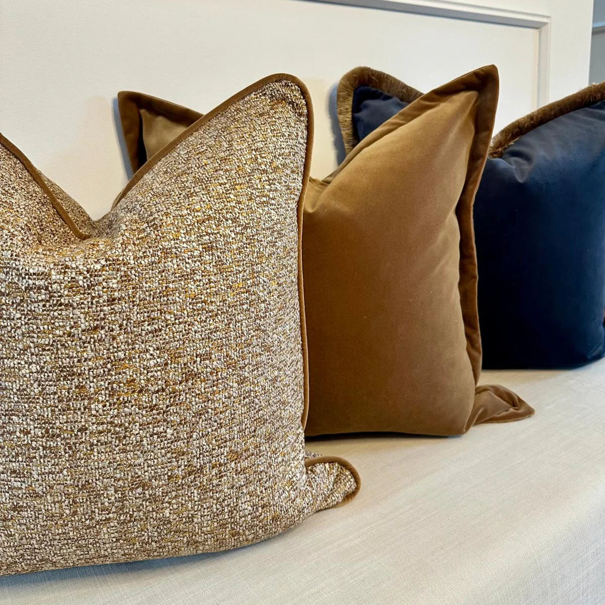 Decorative pillows on a sofa with a gold textured pillow, brown pillow, and blue pillow.