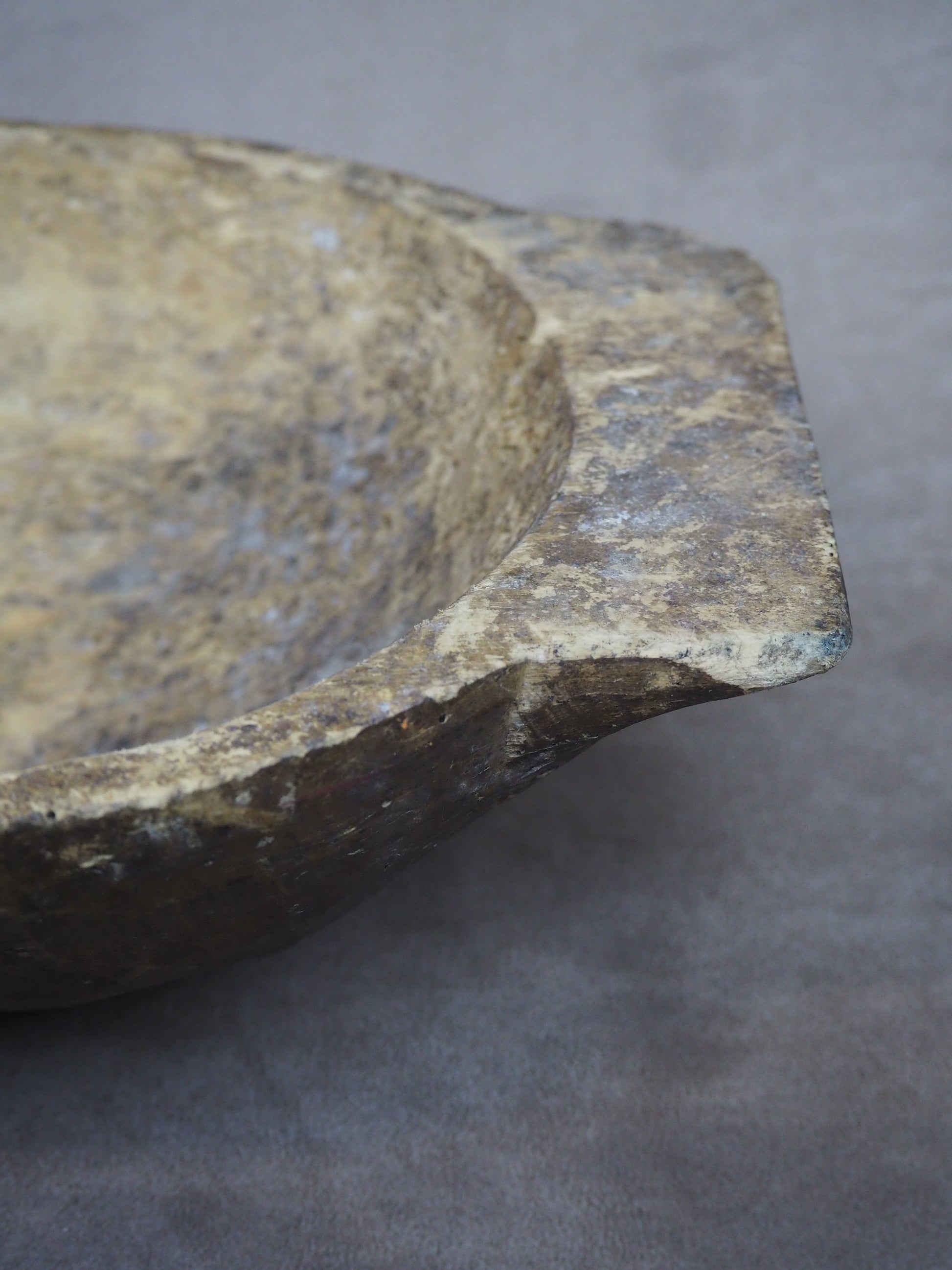 Close-up of an antique dough bowl with a textured surface on a gray background