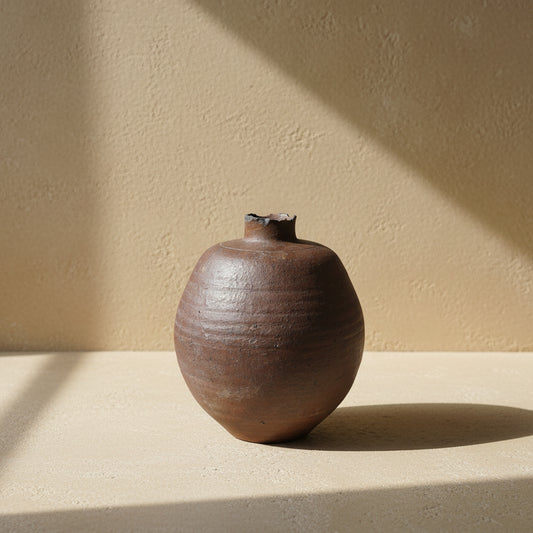 Brown ceramic jar on a textured surface