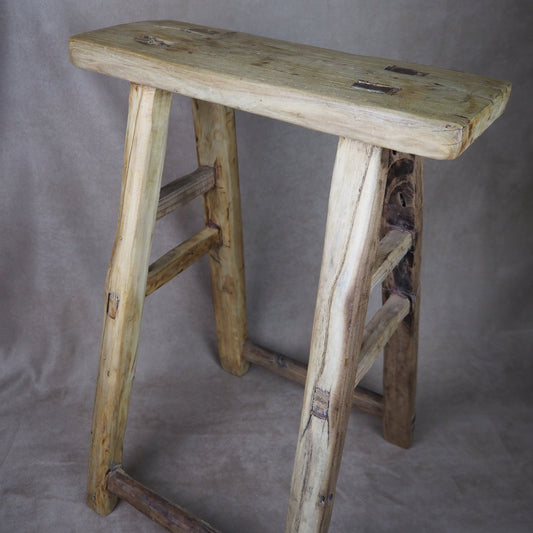 Wooden stool with a textured surface on a gray background