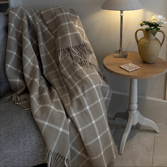 Cozy living room corner with a plaid blanket, lamp, and vase.