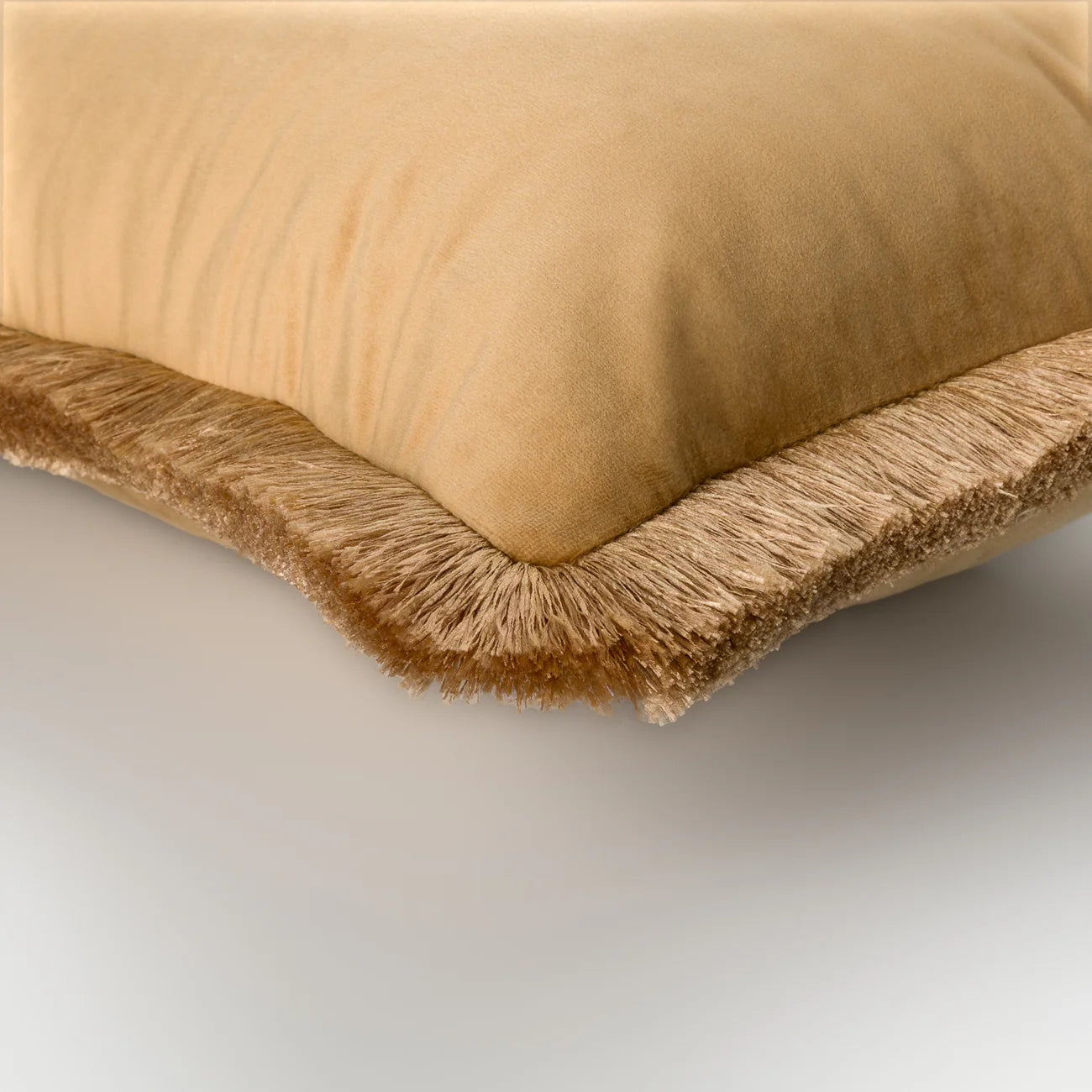 Beige pillow with frayed edge on a light gray background