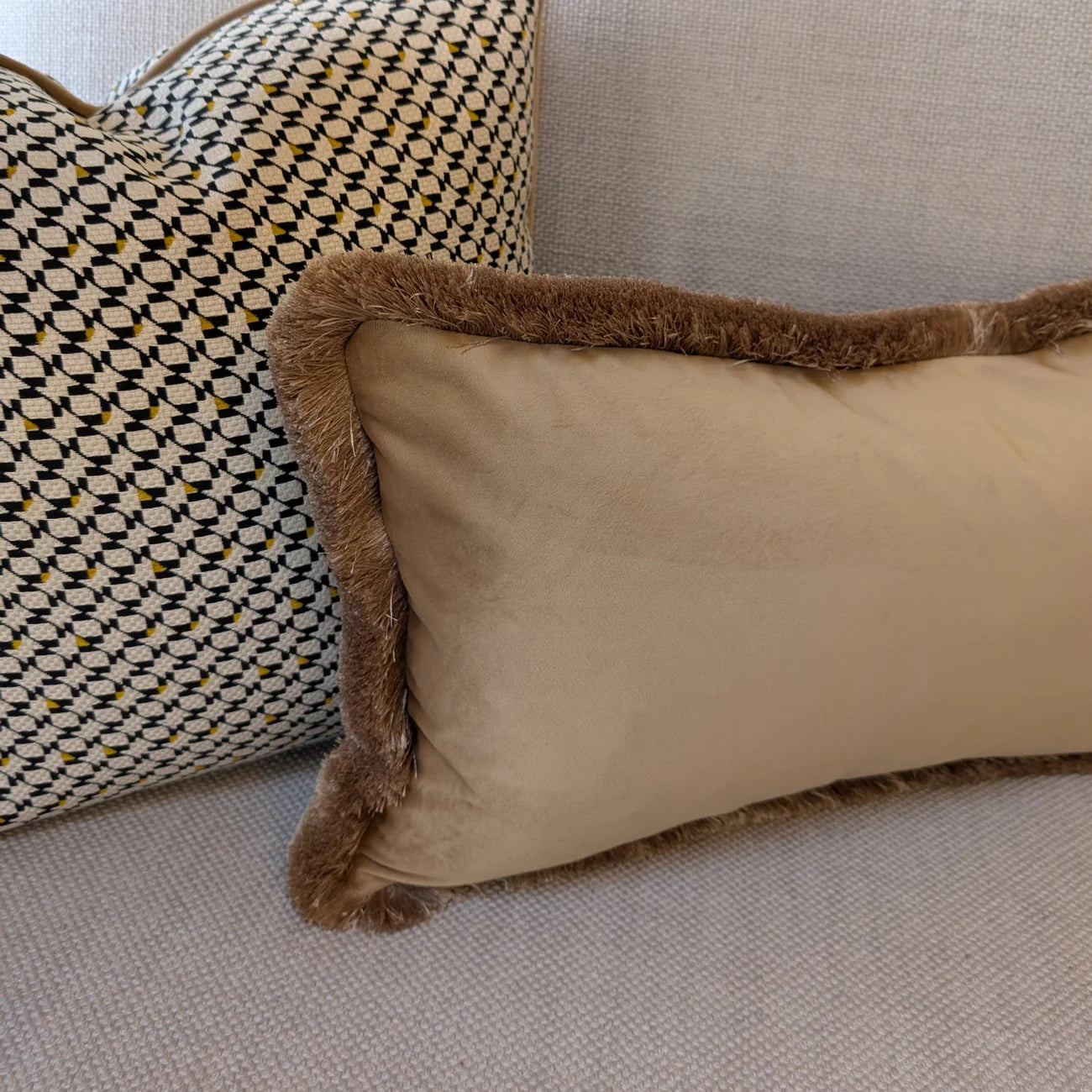 Beige pillow with brown trim on a beige sofa