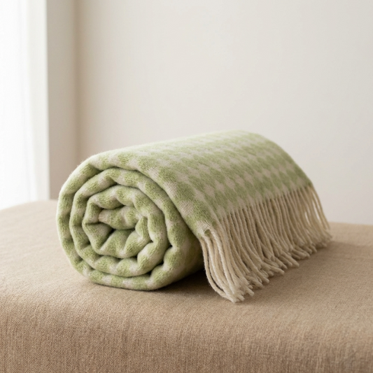 Rolled green blanket with fringe on a beige surface