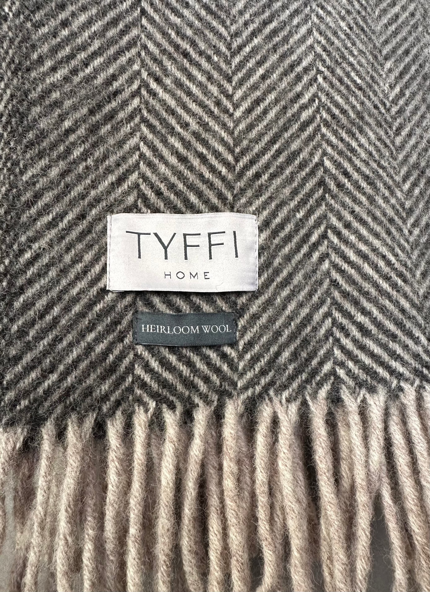 Gray herringbone patterned blanket with 'Tyffi Home' label