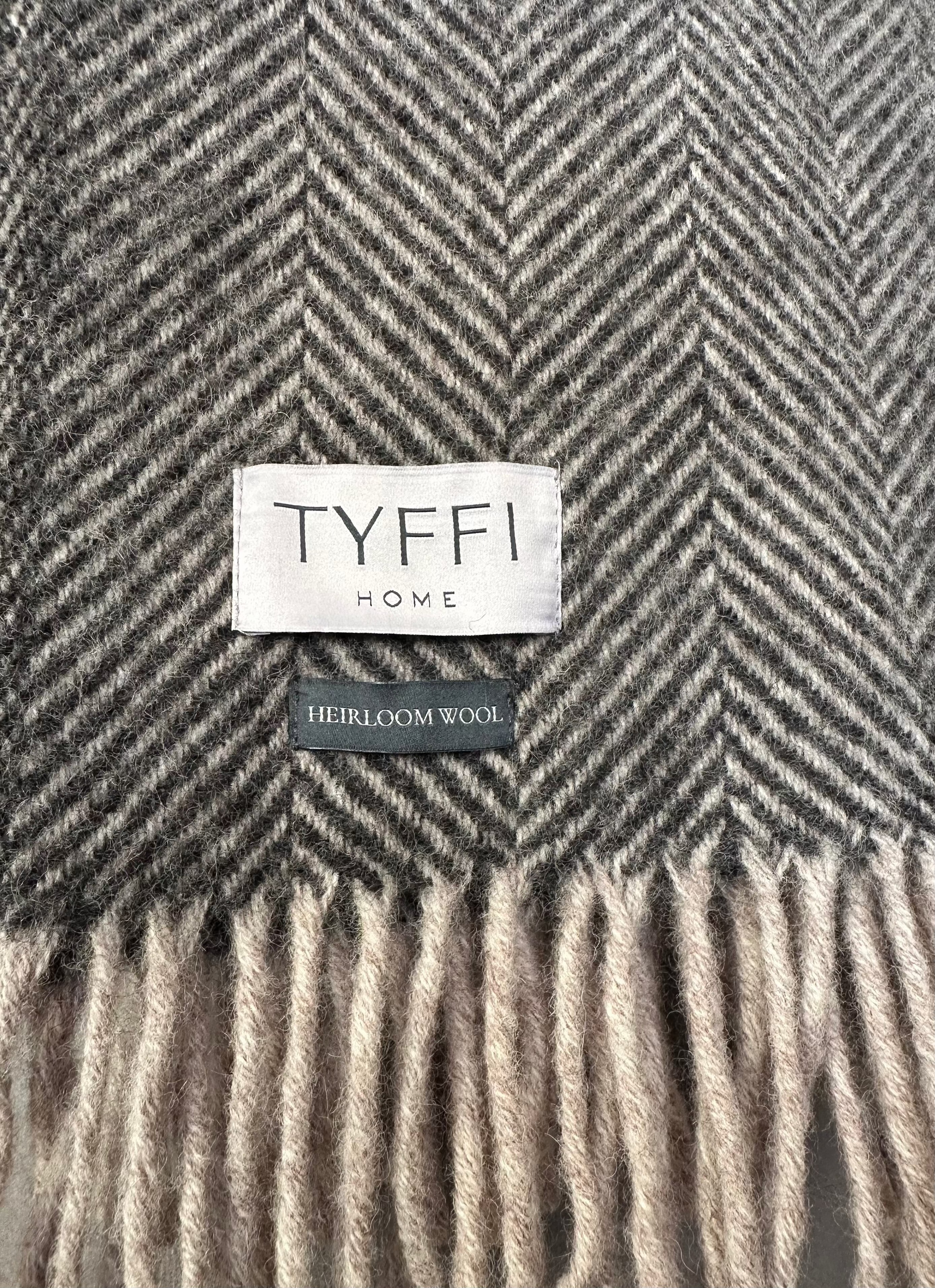 Gray herringbone patterned blanket with 'Tyffi Home' label