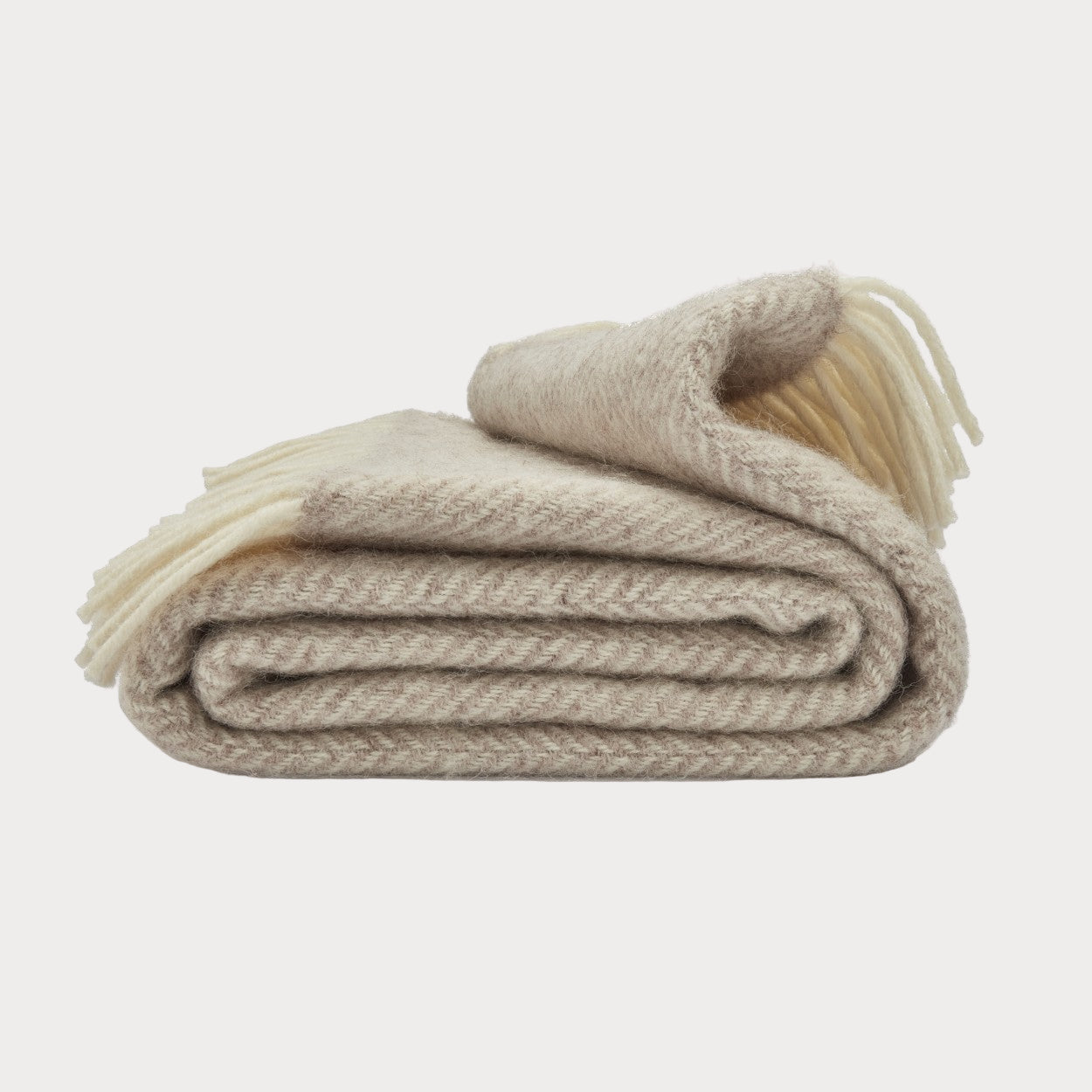Folded beige blanket with tassels on a white background