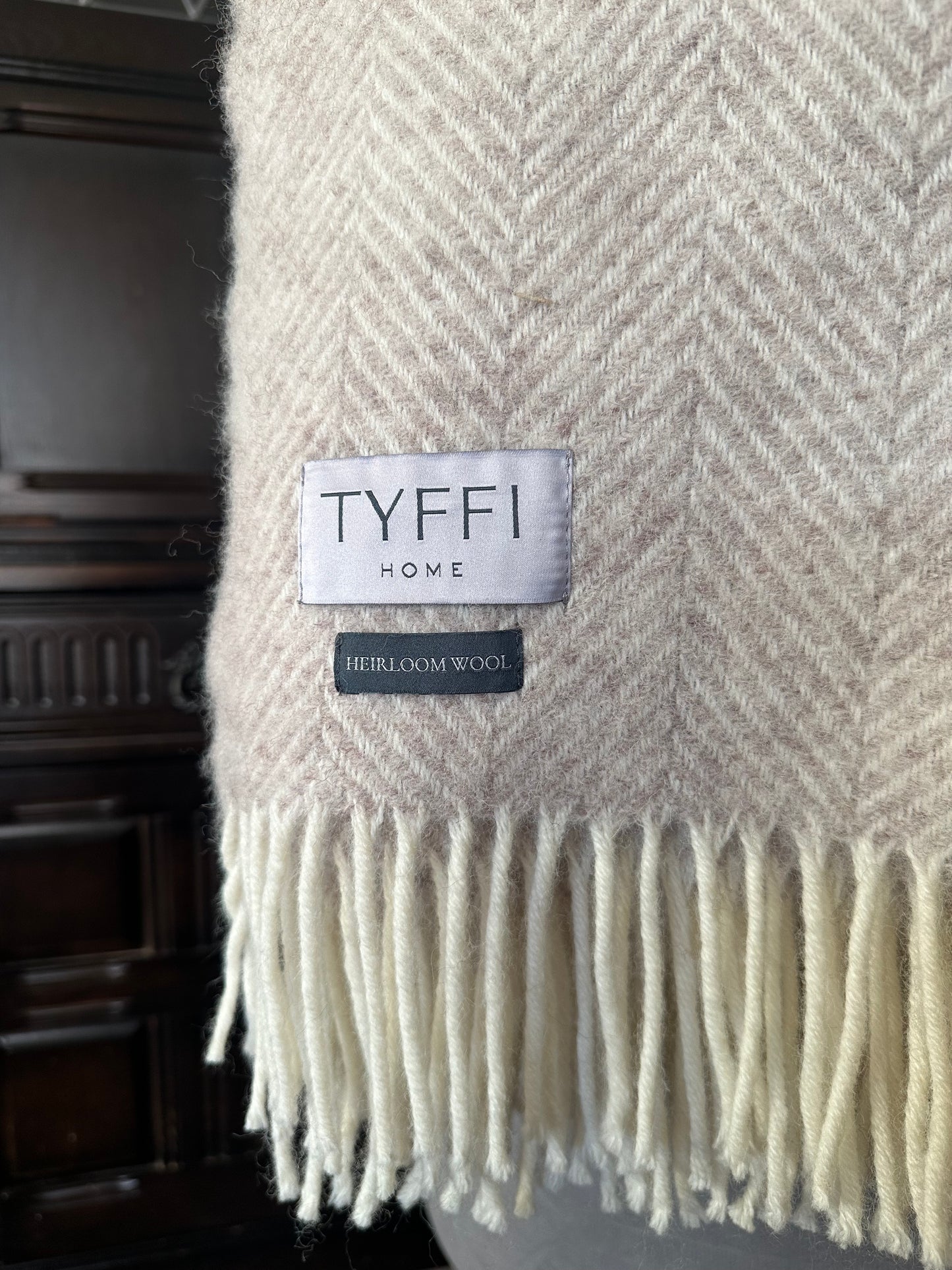 Beige herringbone patterned throw blanket with 'Tyffi Home' label on a dark background