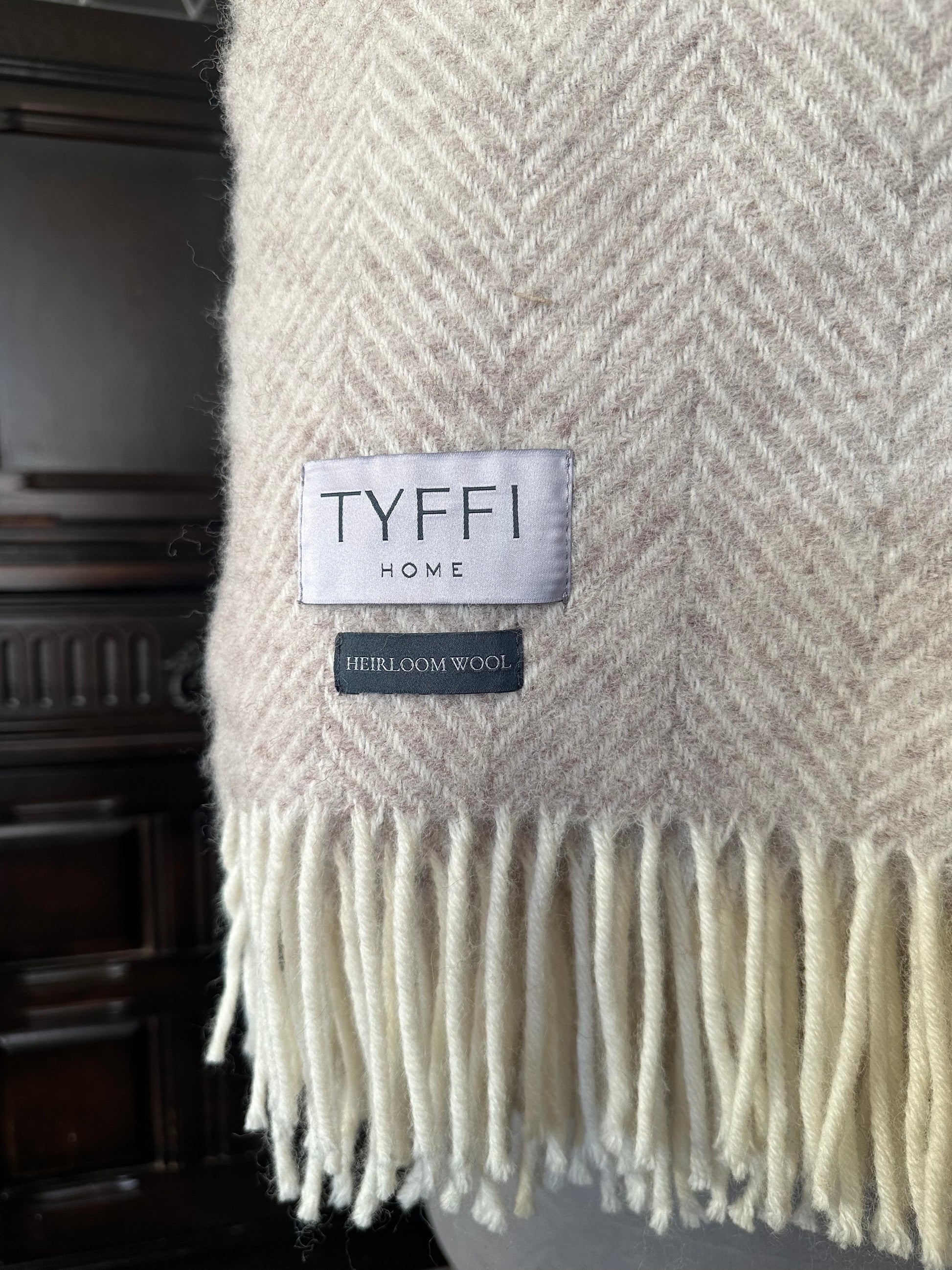Beige herringbone patterned throw blanket with 'Tyffi Home' label on a dark background